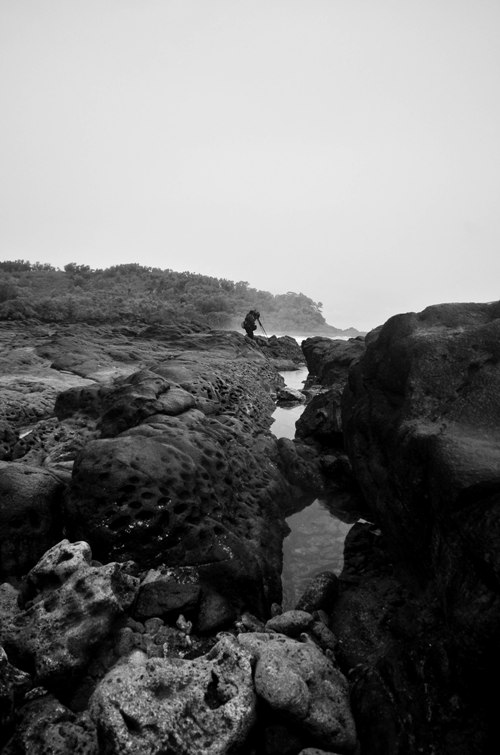 Fotografer melintasi karang untuk memotret ombak